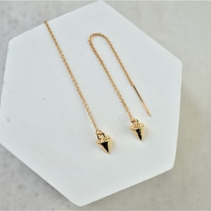 May include: A pair of gold dangle earrings with a pointed, triangular charm at the end of each chain.
