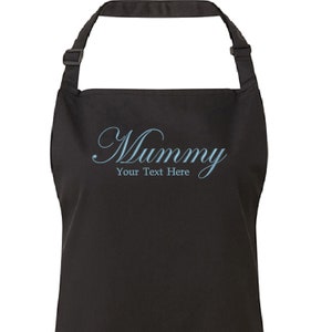 Op de afbeelding: Zwarte schort met de tekst "Mummy" in een blauw cursief lettertype en de woorden "Your Text Here" in een kleiner lettertype eronder.
