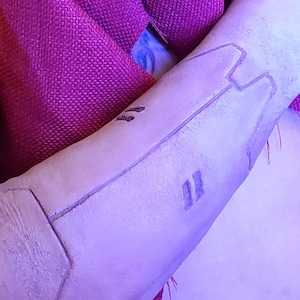 May include: A person's arm with a tattoo of Japanese characters and a geometric design drawn on the skin with a black marker.