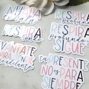 May include: A set of colorful stickers with Spanish motivational phrases. The stickers feature a variety of colors, including pink, blue, and white. The phrases include "Inhala exhala", "Respira profundo", "Respira hondo", "Vantate dira sonrie adelante", "Tu presente no es para siempre", and "Sigue".