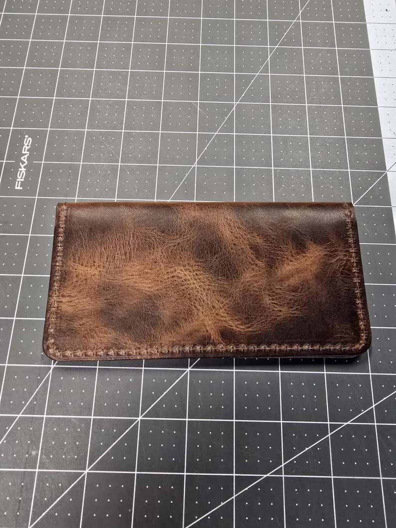 May include: A brown leather wallet with a distressed finish and stitching around the edges.