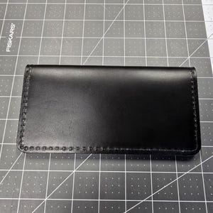 May include: A black leather wallet with a stitched edge.
