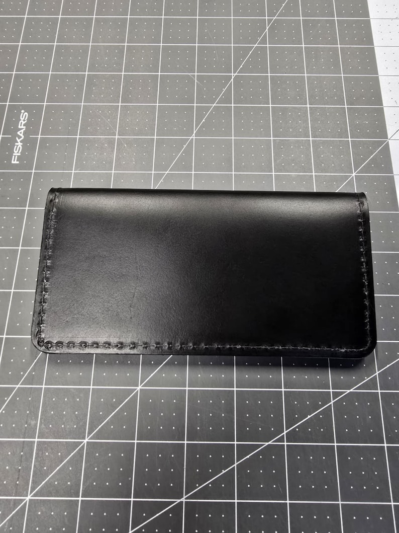 May include: A black leather wallet with a stitched edge.