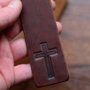 May include: A brown leather bookmark with a cross embossed on the front.