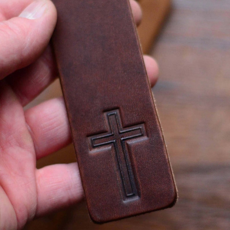 May include: A brown leather bookmark with a cross embossed on the front.