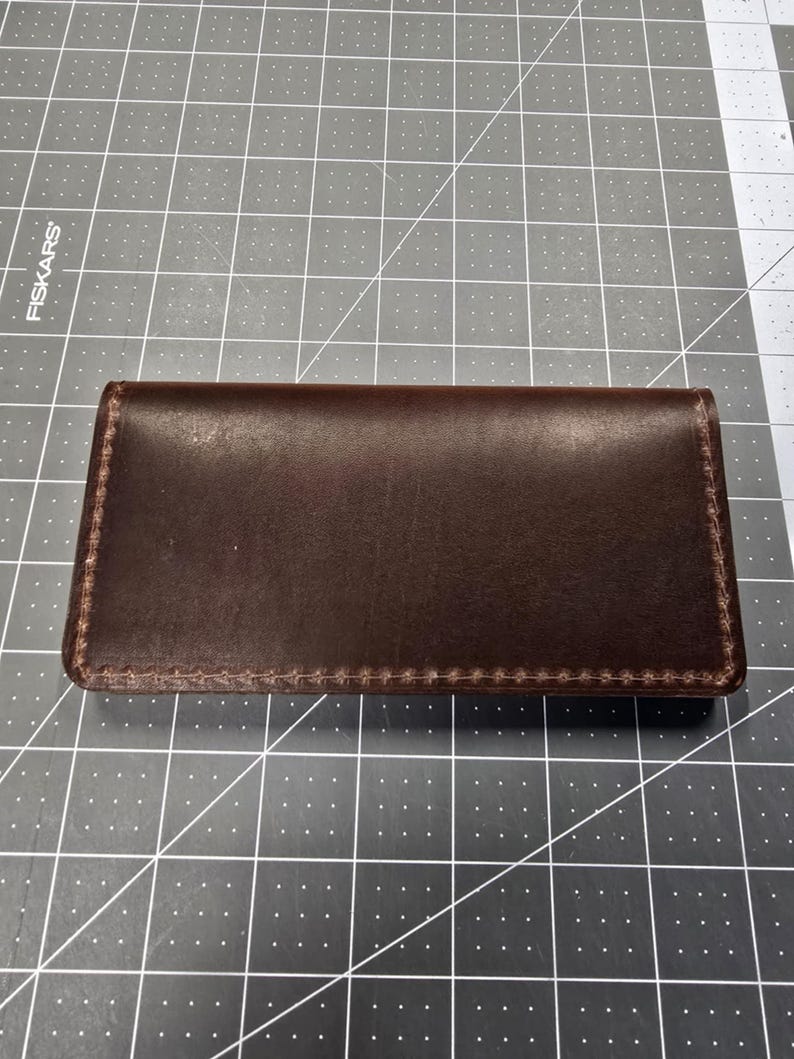 May include: A brown leather wallet with a stitched edge.