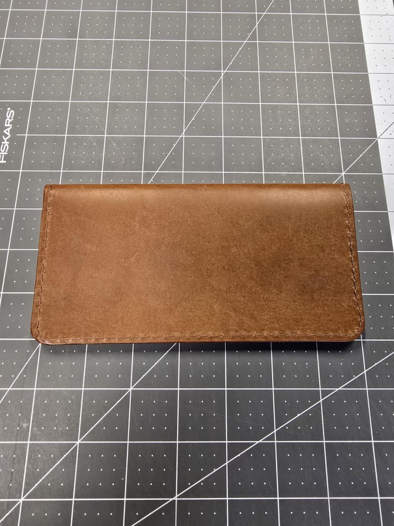 May include: A brown leather wallet with a stitched edge.