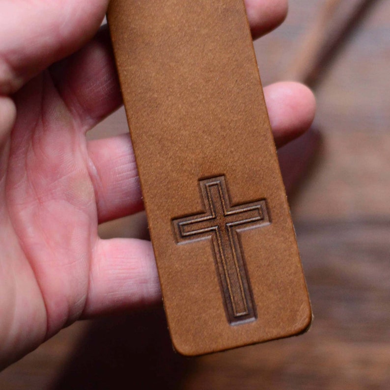 May include: A brown leather bookmark with a cross embossed on the front.