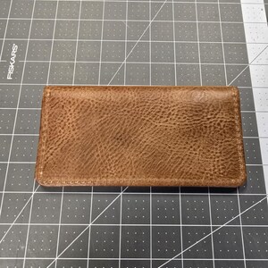 May include: A brown leather wallet with a textured surface.