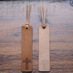 May include: Two brown leather bookmarks with tassels. One bookmark has a cross design.