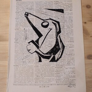 Könnte beinhalten: Abstrakte schwarze Tinte Zeichnung auf einer Vintage-Buchseite. Das Kunstwerk zeigt eine geometrische Figur mit einem kreisförmigen Element, vor einem Hintergrund aus gealtertem Text.