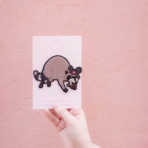 Parche bordado para planchar con diseño de Bob's Burgers y gorro de Mickey con mapache