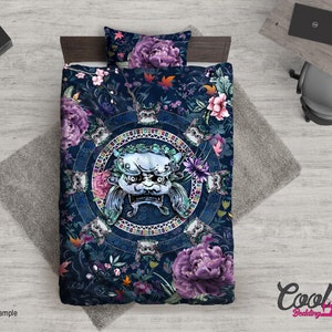 May include: A blue and purple bedding set featuring a floral pattern and a large, detailed, white and grey mythical creature in the centre. The creature has a fierce expression and is surrounded by a circular design.
