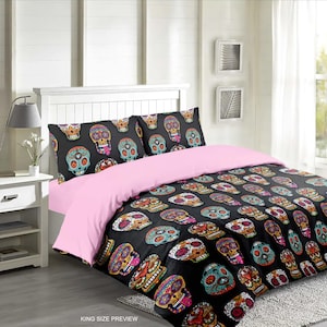 May include: A king-size bed with a pink duvet cover and black and white patterned pillowcases. The duvet cover features a repeating pattern of colorful sugar skulls.