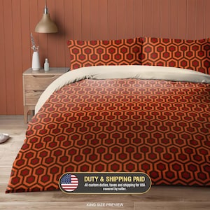 Può includere: Un set di biancheria da letto king size con un motivo geometrico a esagoni ripetuto nei toni dell'arancione, rosso e marrone scuro. Il set include un copripiumino e due federe abbinate, completato da un bordo superiore beige.