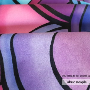 May include: Close-up of a purple, pink, and blue fabric with a geometric pattern. The fabric is smooth and has a subtle sheen. The text "800 threads per square inch" and "Fabric sample" is printed on the fabric.