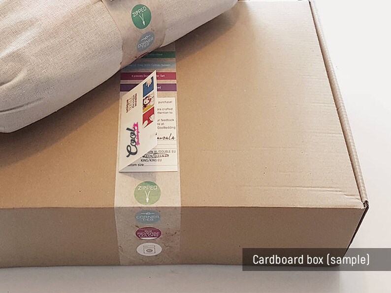 May include: A brown cardboard box with a white fabric item inside. The box has labels with the words "Cool", "Zipped", and "Discover Then". The box is labeled "Cardboard box (sample)".