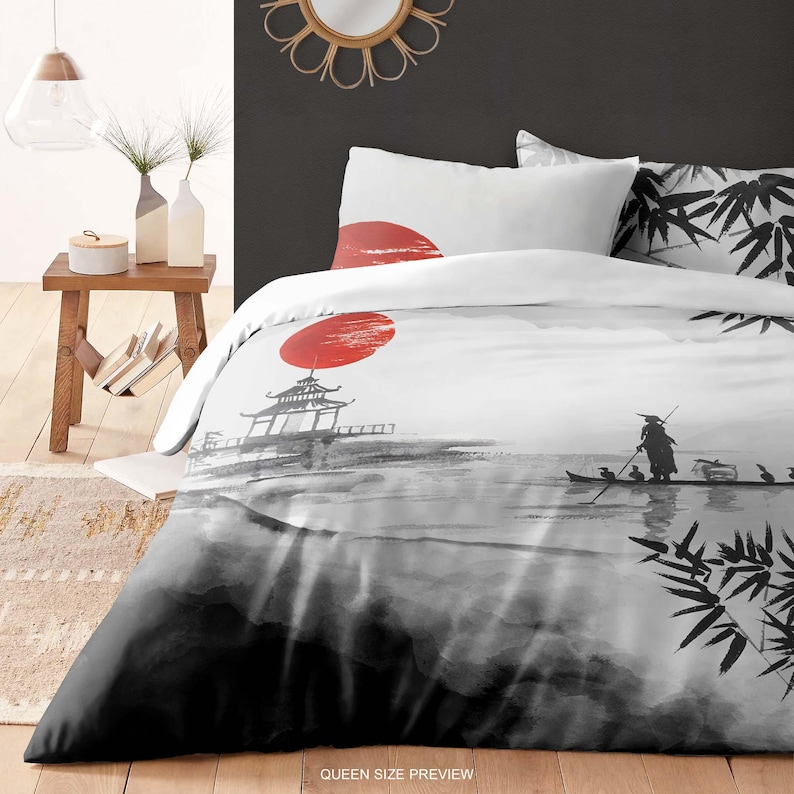 May include: A black and white duvet cover with a Japanese-inspired design. The design features a red sun, a pagoda, a person in a boat, and bamboo leaves. The duvet cover is shown on a bed with white pillowcases.
