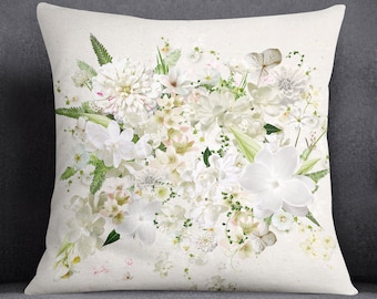 May include: White throw pillow with a floral design featuring a bouquet of white flowers with green leaves.