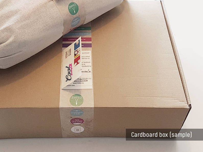 Pu&ograve; includere: Una scatola di cartone marrone con un articolo di tessuto bianco all'interno. La scatola ha etichette con le parole "Cool", "Zipped" e "Discover Then". La scatola &egrave; etichettata "Scatola di cartone (campione)".