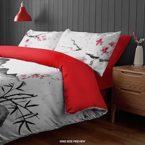 May include: A king-size bedding set with a white and gray duvet cover featuring a black and white bamboo design and pink watercolor flowers. The set includes two pillowcases with a white and gray background and pink watercolor flowers. The duvet cover is red on the reverse side.
