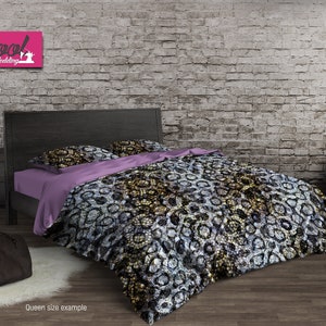 Puede incluir: Una cama de tamaño queen con una cabecera negra y una funda nórdica estampada. La funda nórdica presenta un patrón abstracto en negro, blanco y dorado. La cama está sobre un suelo de madera marrón claro. El texto "Cool Bedding" es visible en la esquina superior izquierda de la imagen.