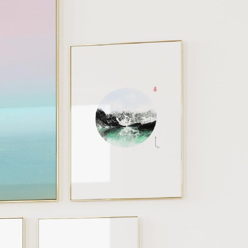 May include: A framed print of a black and white watercolor painting of a mountain scene with a green lake. The painting is in a circle shape and is on a white background.