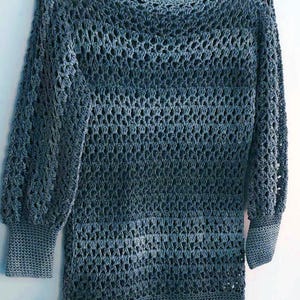 Op de afbeelding: Een blauwe gehaakte trui met een los, opengewerkt ontwerp. De trui heeft een boot hals en lange mouwen.