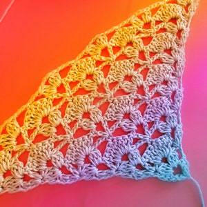 Könnte beinhalten: Ein gehäkeltes Dreieckstuch mit einem Farbverlauf von Gelb über Lila bis Blau.