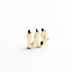 May include: A gold-colored metal charm in the shape of the letter "W".