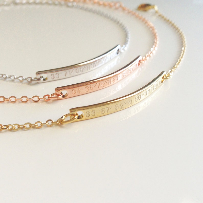 May include: Three gold, rose gold, and silver bracelets with delicate chains and engraved coordinates. The coordinates are 33 71/08/N 80-59-12, 34 35/79/N 80-59-12, and 33 57/82/N 60-01-43.
