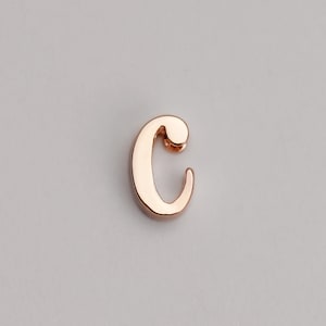 May include: A rose gold letter C charm. The letter is in a cursive font.