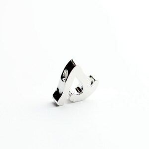 May include: A silver charm in the shape of a musical note with a small clear stone on the side.
