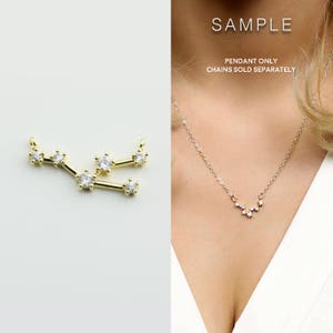 May include: Gold pendant necklace with a constellation design featuring small clear cubic zirconia stones. The pendant is shaped like the constellation Ursa Major, also known as the Big Dipper. The text "SAMPLE PENDANT ONLY CHAINS SOLD SEPARATELY" is displayed on a white background.