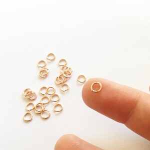 May include: A close-up of a pile of small gold jump rings. The rings are about 5mm in diameter and are perfect for jewelry making.