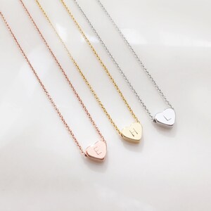 May include: Three delicate necklaces with heart-shaped pendants. Each pendant features a different initial: E, H, and L. The necklaces are available in rose gold, gold, and silver.