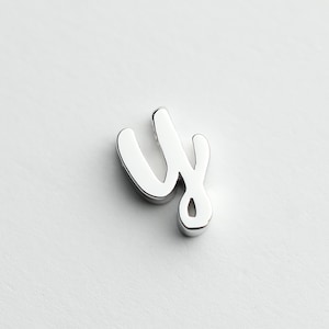 May include: A silver charm in the shape of the letter "y" in a cursive font.