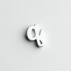 May include: A silver charm in the shape of the letter 'q'.