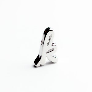 May include: A silver charm in the shape of a stylized letter 'k'.
