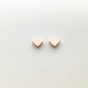 May include: A pair of rose gold heart-shaped stud earrings.