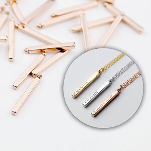 May include: Three gold bar necklaces with different engraved text. The necklaces are on a white background. The text on the necklaces reads "MR - > TO", " - > XTR", and "<3 MON - > 4VM".