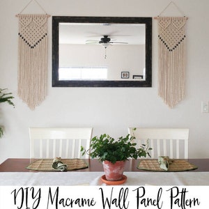 May include: Two macrame wall hangings with a geometric pattern and black accents hang on a white wall above a wooden table with two white chairs. A potted plant sits on the table between the chairs. The text "DIY Macrame Wall Panel Pattern" is at the bottom of the image.