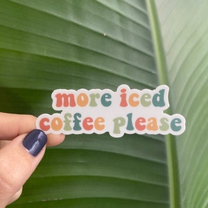 Puede incluir: Una pegatina blanca con el texto "more iced coffee please" en letras de colores de estilo retro.