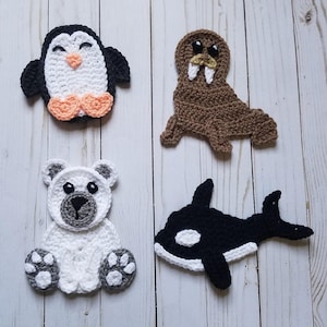 May include: Four crocheted animal appliques: a penguin with orange feet, a brown walrus, a white polar bear, and a black and white orca whale.