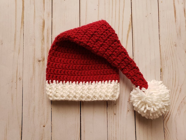 May include: A red and white crocheted Santa hat with a white pom-pom on the end.
