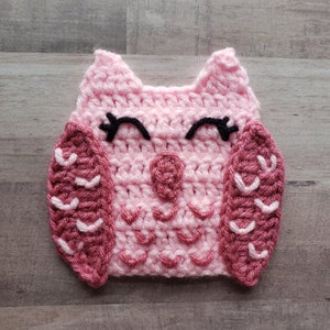 Puede incluir: Un b&uacute;ho de crochet rosa con ojos negros y alas rosas y blancas.