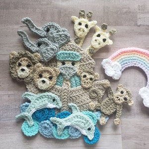May include: A set of crocheted animal and nature-themed appliques, including a giraffe, elephant, bear, monkey, dolphin, and a rainbow. The appliques are made in shades of brown, grey, blue, and pink.
