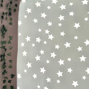 May include: A sage green fitted sheet with a white star pattern. The sheet is made of soft, breathable fabric and is perfect for a nursery or child's bedroom.