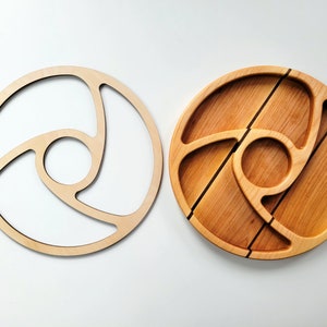 Op de afbeelding: Twee houten serveerschalen, een met een uitgesneden ontwerp en de andere met een gesneden ontwerp. Beide schalen zijn rond en gemaakt van licht hout.
