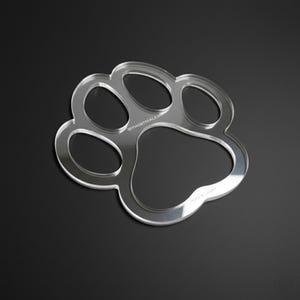 May include: Clear acrylic paw print shape with rounded edges, designed with five distinct sections. The text "DIYMONTREAL.COM" is visible on the top left, and "Made in Canada" is on the bottom right. The object is on a black background.